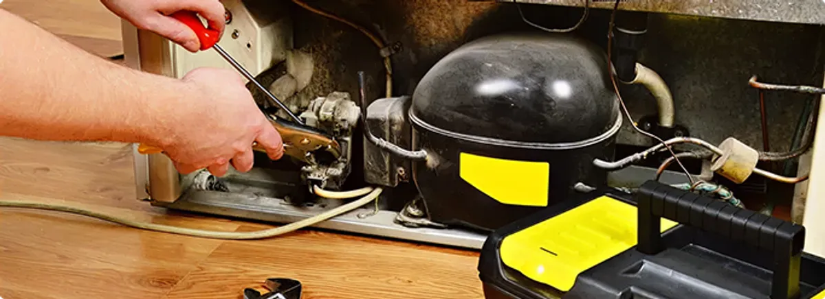 Refrigerator repair technician fixing the compressor and wiring in Martell, NE