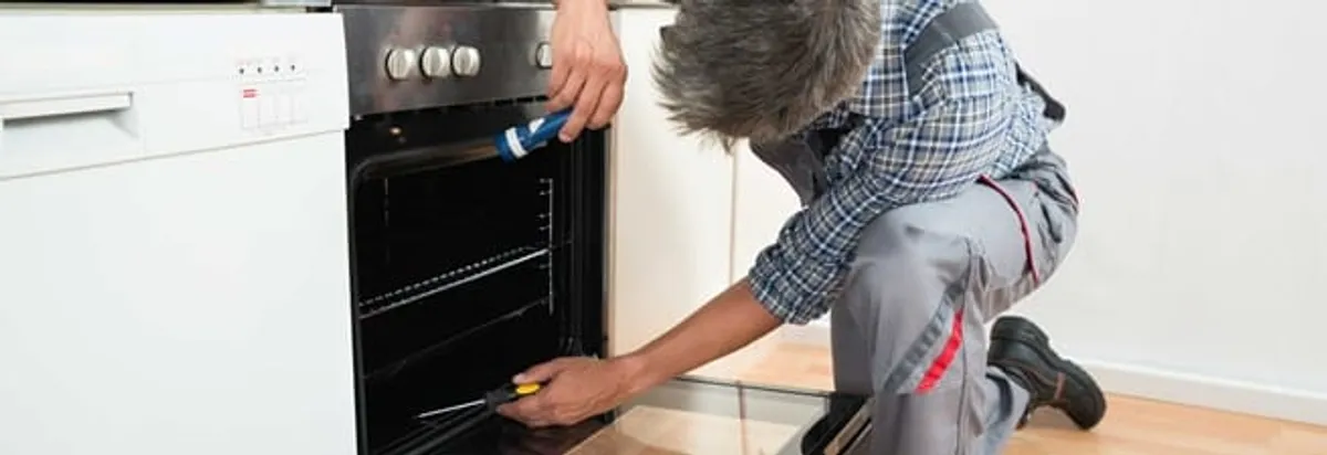 Oven repair technician inspecting and servicing an electric oven in Lincoln, NE
