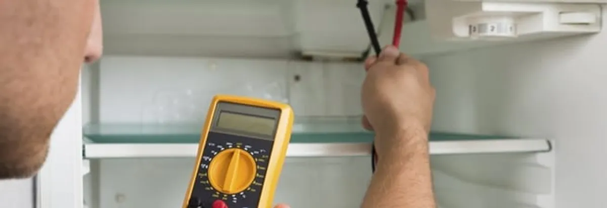 Refrigerator repair technician testing electrical components with a multimeter in Lincoln, NE